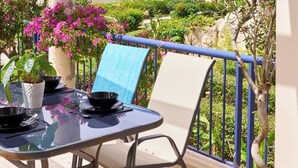 A terrace with a table set for dining, overlooking a scenic view of the sea and a building. - Villa Elias 1BR Upper Apt with Pool (Maleme)