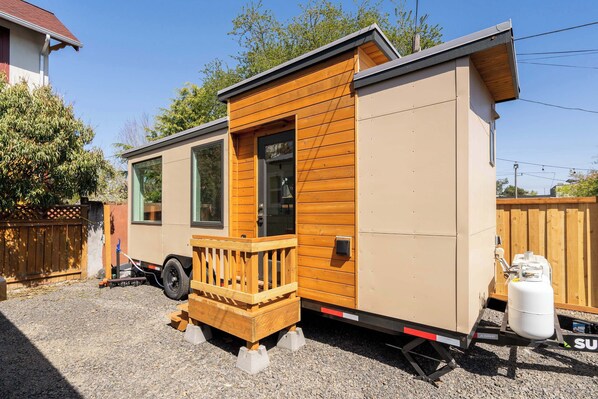 Une maison mobile dotée d’une terrasse en bois, d’une porte coulissante et d’une cuve à propane.