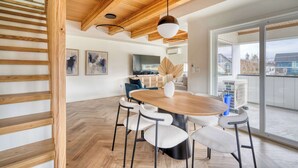 Un comedor moderno con una mesa de madera, sillas blancas y un techo con vigas a la vista.