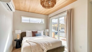 Un dormitorio con cama, dos mesitas de noche, una ventana y vistas al exterior.