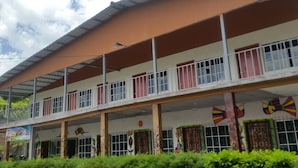 A multi-story building with a flat roof and a covered walkway. - Hotel Arbol de Paz (San Ignacio)