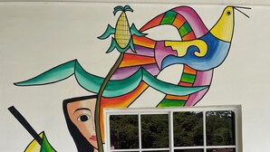 A colorful mural on a wall with a window, a chair, and a tiled floor. - Hotel Arbol de Paz (San Ignacio)