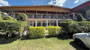 A building with a covered entrance, multiple windows, and colorful murals on the walls. - Hotel Arbol de Paz (San Ignacio)