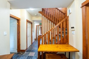 A wooden staircase with a carpeted landing, a white door on the left, and a light-colored wall.