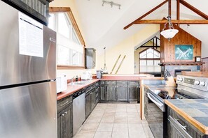 Una cucina con frigorifero in acciaio inossidabile, lavastoviglie, piano cottura e pensili in legno.