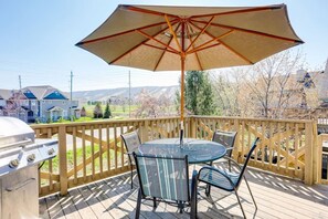 Una terrazza con tavolo e sedie, un barbecue e un ombrellone grande.