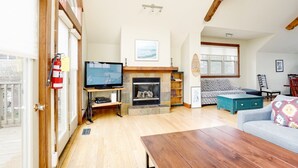 Een ruime woonkamer met een open haard, een televisie en een bank.