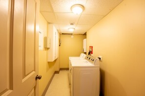 A laundry room with a washing machine and dryer, a door, and a ceiling light.