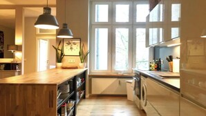 A modern kitchen with a wooden island, pendant lighting, a view through large windows, and a built-in washing machine.