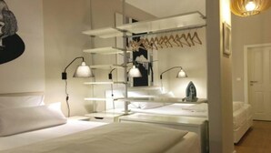 A modern hotel room with a large bed, bedside tables, a desk, and a hanging light fixture.