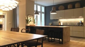 A modern kitchen with a wooden island, pendant lights, and a dining area with chairs.