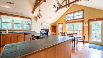 A kitchen with a large island, wooden cabinets, and a dining area with a table and chairs.
