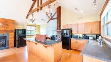 A spacious kitchen with a central island, wooden cabinets, and a stone fireplace.