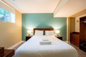 A hotel room with a large bed, two bedside lamps, a wooden wardrobe, and a window with a view.