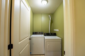 A laundry room with two washing machines and a ventilation duct.
