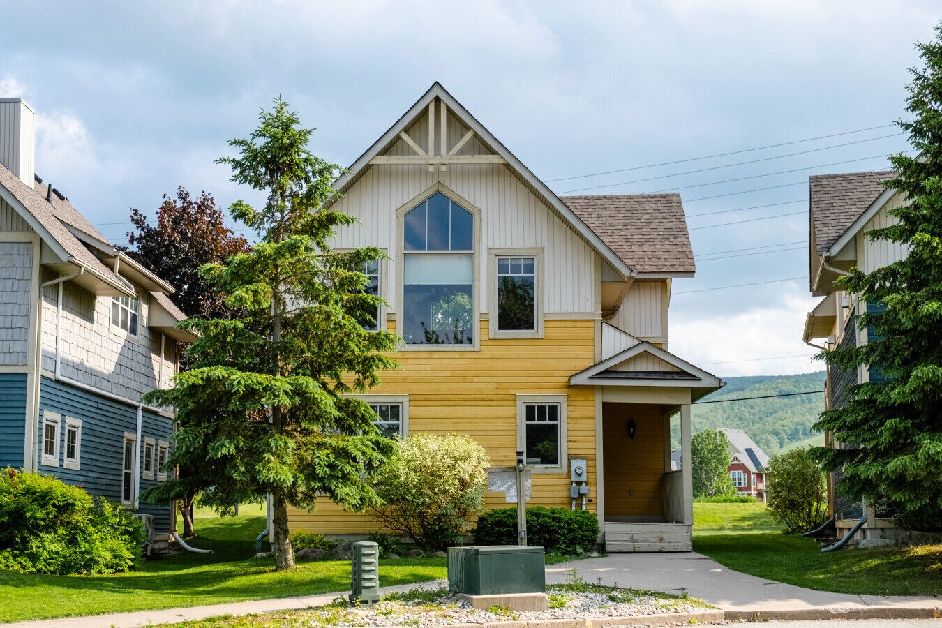 A two-story residential building with a gabled roof, large windows, and a front porch.