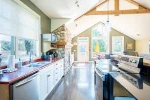 A kitchen with a stone wall, a built-in oven, and a dining area with a table and chairs.