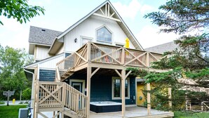 A two-story house with a wooden deck, a front porch, and a visible hot tub. - The Stella at Blue View Chalet (The Blue Mountains)