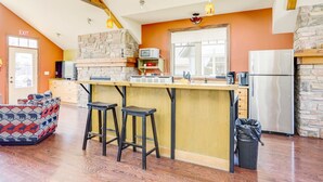 Una cocina con protector antibacteriano de piedra, taburetes de bar de madera, refrigerador de acero inoxidable y un microondas.