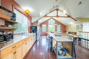 A spacious kitchen with wooden cabinets, a large island, and a stone fireplace.