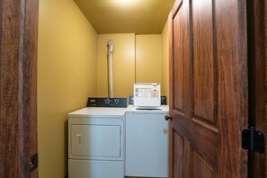A laundry room with a washing machine and dryer, a vent pipe, and a wooden door.