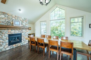 A dining area with a stone fireplace, wooden table, and chairs. - The Prima at Blue View Chalets (The Blue Mountains)