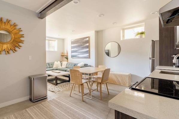 A modern kitchen with a dining area, a compact refrigerator, and a built-in oven.
