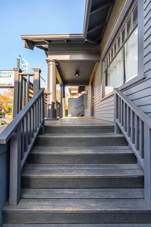 A staircase leading to a building entrance with a metal railing and a covered porch area. - Classic Craftsman Stay - 3BR 2BA - Portland Charm (Portland)