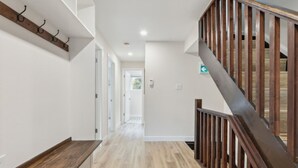 A modern interior with a wooden staircase, a hallway with a wooden floor, and a coat rack. - The 44L at Blue View Chalets (The Blue Mountains)