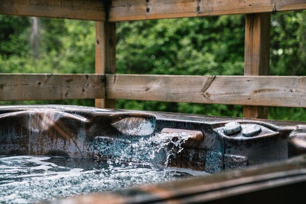 A hot tub with water spouting from the center, surrounded by wooden beams.