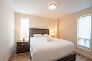 A bedroom with a bed, bedside lamps, a nightstand, and a window.