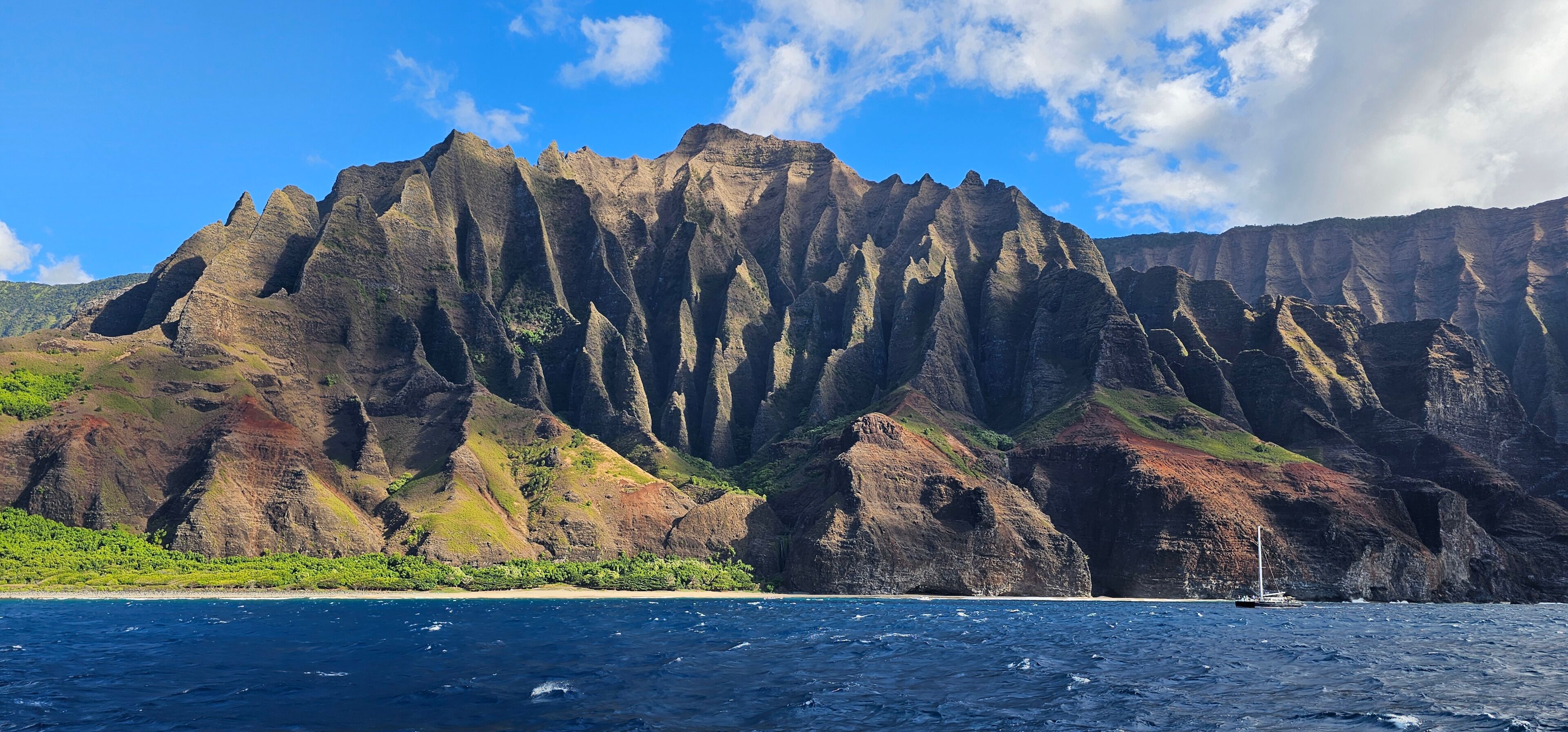 A coastal landscape with a prominent mountain range, a beach, and a body of water.
