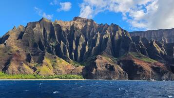 A coastal landscape with a prominent mountain range, a beach, and a body of water.