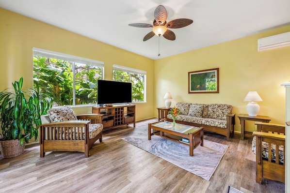 Relax in this inviting living room with a high ceiling fan, flat-screen TV, and comfortable seating area.