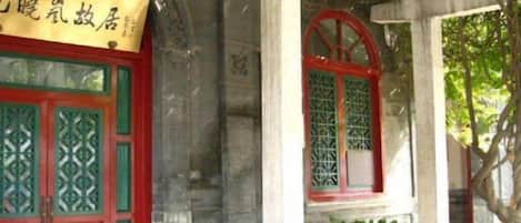 Un edificio tradicional con puertas y ventanas rojas, un acceso cubierto y una estructura de piedra.