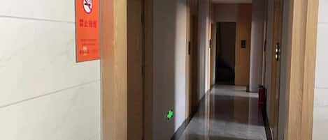 A hotel corridor with signs indicating no smoking and a fire exit.