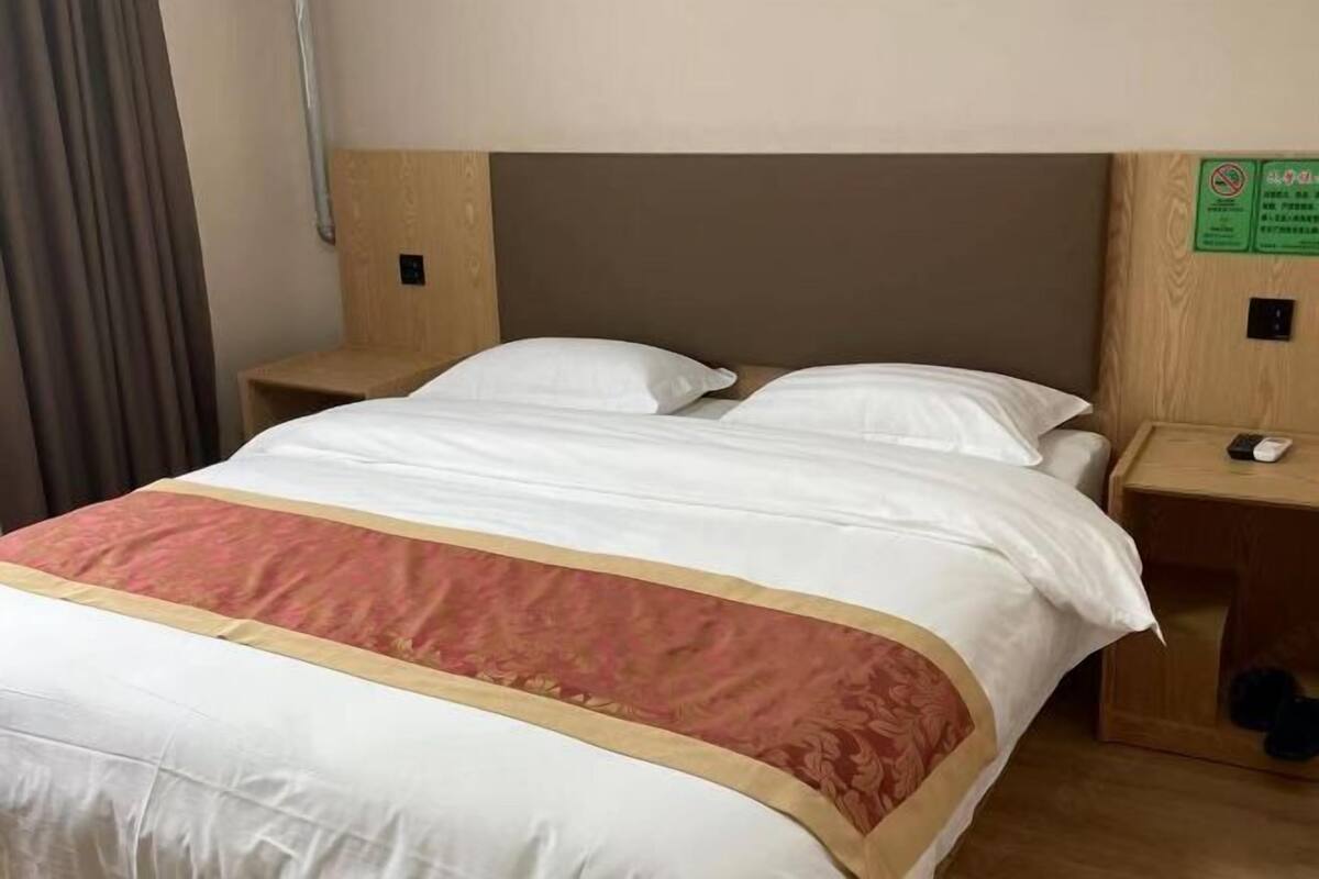 A hotel room with a bed, two bedside tables, and a headboard.