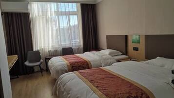 A hotel room with two beds, a desk, a chair, and a window with curtains.