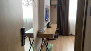 Ein Hotelzimmer mit einem Holztisch, einem Fernseher und einem grünen Wäschekorb.