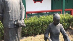 Eine Statue eines Mannes, der eine Schriftrolle und ein Kind hält.