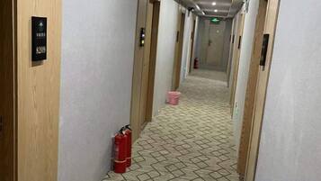 En hotellkorridor med trädörrar, en brandsläckare och ett mönstrat golv.