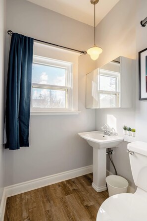 Bathroom with a pedestal sink, a toilet, and a window. - Remodeled 3BR - Walk to Coffee, Bars & More (Portland)