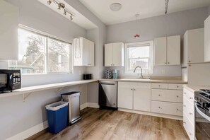 A modern kitchen with white cabinets, a dishwasher, a stove, and a microwave. - Remodeled 3BR - Walk to Coffee, Bars & More (Portland)