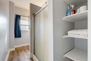 A bathroom with a shower, a towel rack, and a shelf with toiletries. - Remodeled 3BR - Walk to Coffee, Bars & More (Portland)