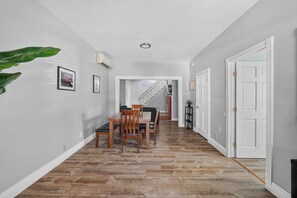 A hallway with a dining table and chairs, a staircase, and a door. - Remodeled 3BR - Walk to Coffee, Bars & More (Portland)