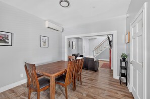 A dining area with a wooden table and chairs, a staircase leading to another room, and a hallway with a door. - Remodeled 3BR - Walk to Coffee, Bars & More (Portland)