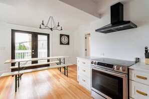 A kitchen with a built-in oven, white cabinetry, and a bench.