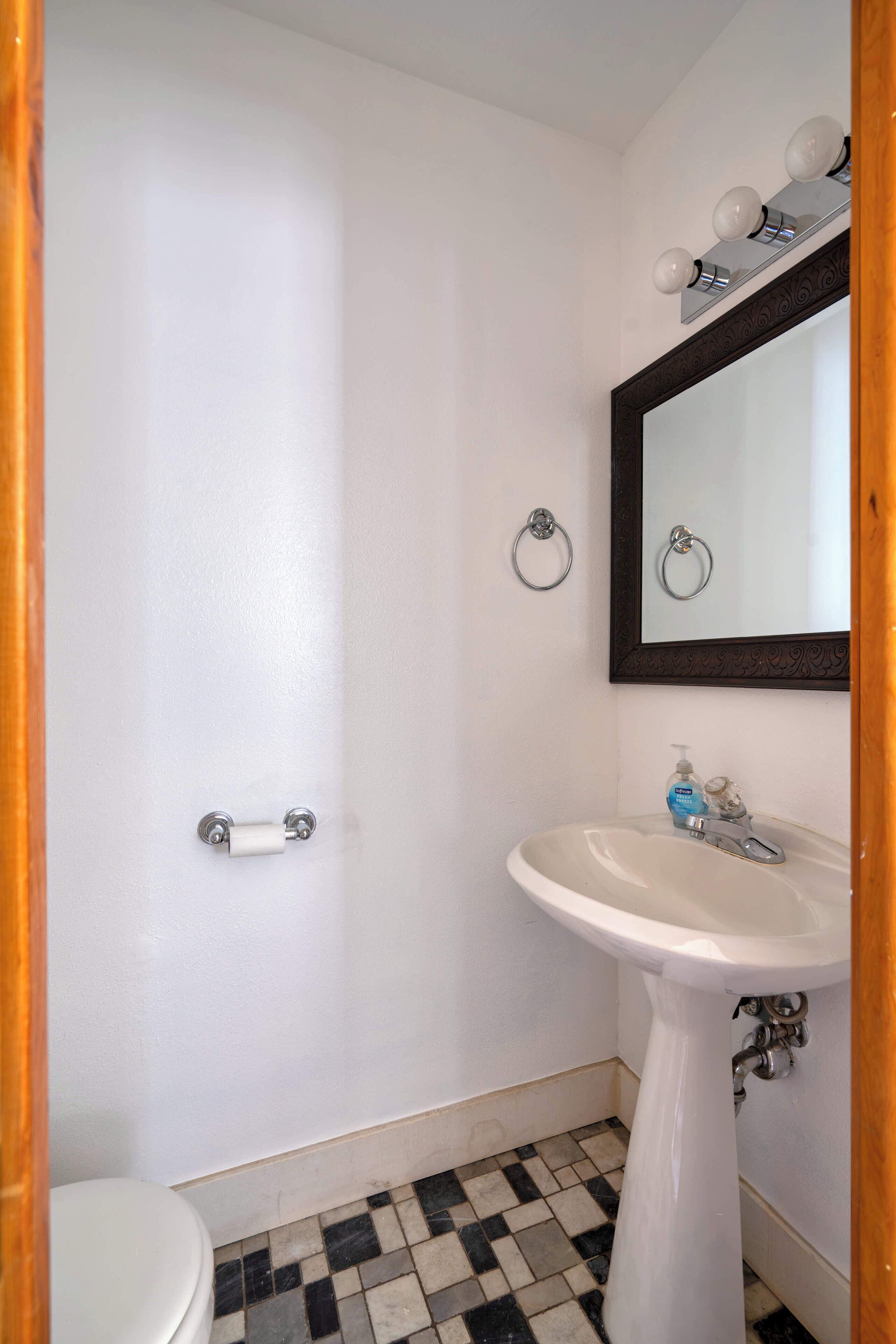 A bathroom with a white sink, a mirror, and a toilet.
