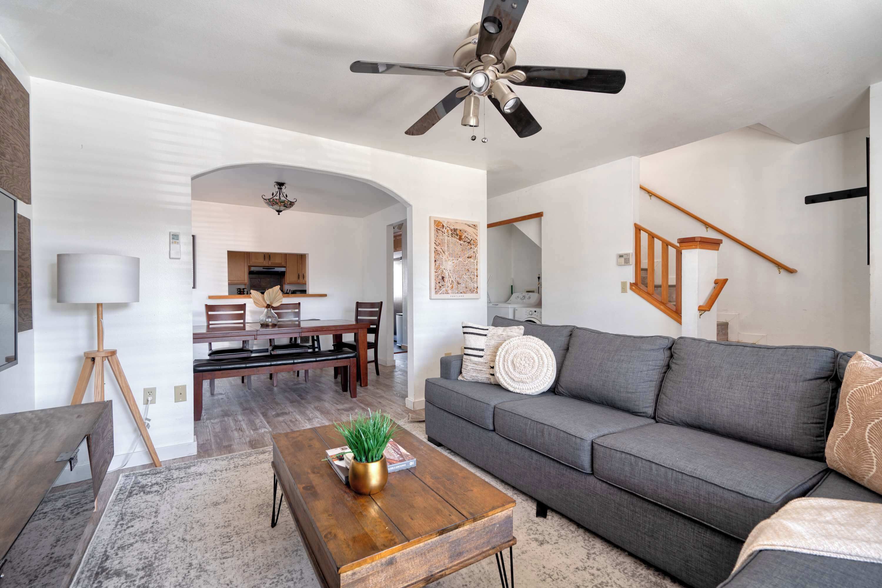 A modern living room with a grey sofa, wooden coffee table, and a ceiling fan.