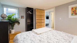 Une chambre à coucher avec un lit, une armoire, une plante et un globe terrestre posé sur une commode.